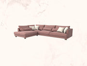 Pink sectional sofa with white cushions on a light pink background